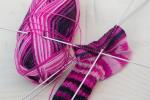 selbstgestrickte Socke in lila Tönen und Stricknadeln© Pixabay