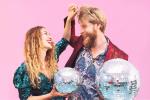 Ein Mann und eine Frau, die zusammen Discofox tanzen mit zwei silbernen Discokugeln in den Händen. Bild © Canva