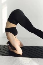 weibliche Person führt Pilates-Übung auf einer schwarzen Matte aus © pexels