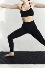 weibliche Person führt Pilates-Übung auf einer schwarzen Matte aus © pexels
