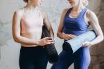 zwei weibliche Personen unterhalten sich mit ihren Pilates-Matten unter den Armen © pexels