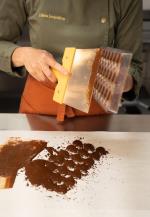 Frau schabt Pralinen in der Form glatt © Pralilinen