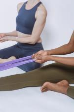 Personen dehnen sich mit Bändern auf dem Boden © Pexels